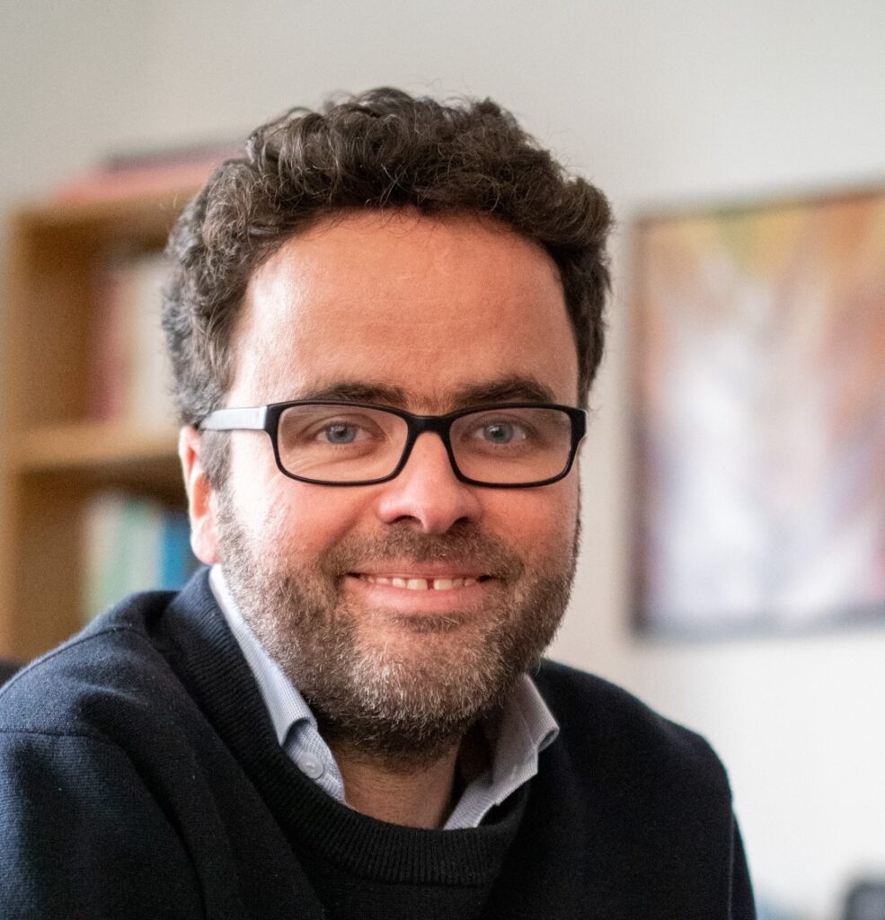 Profile picture of Peter, a white man nearing 40. He has short dark curly hair, a close cropped beard, glasses, and a smile.